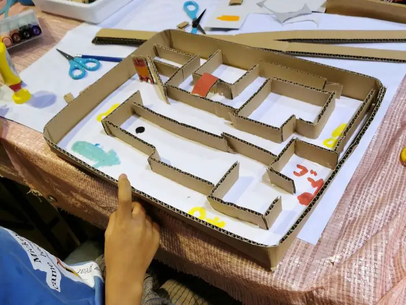 A child is using cardboard to build a maze.