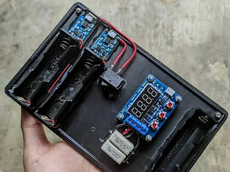 A person DIY testing a small electronic device's battery.