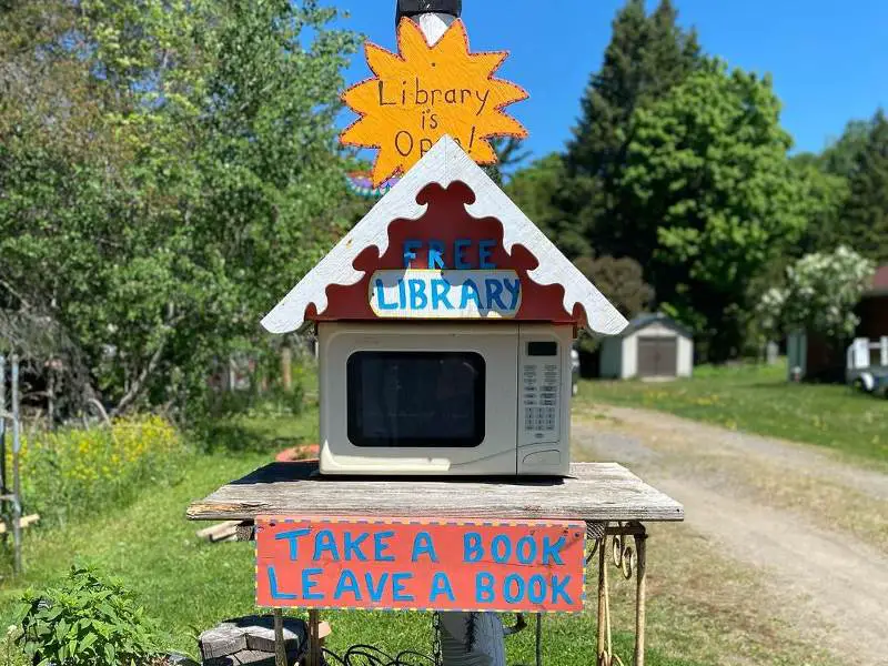 A microwave repurposed as a library with a sign that says take a book and leave.