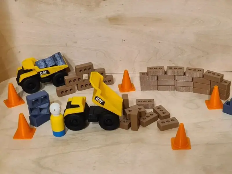 A construction set with a yellow dump truck and orange cones that can be utilized for art projects.